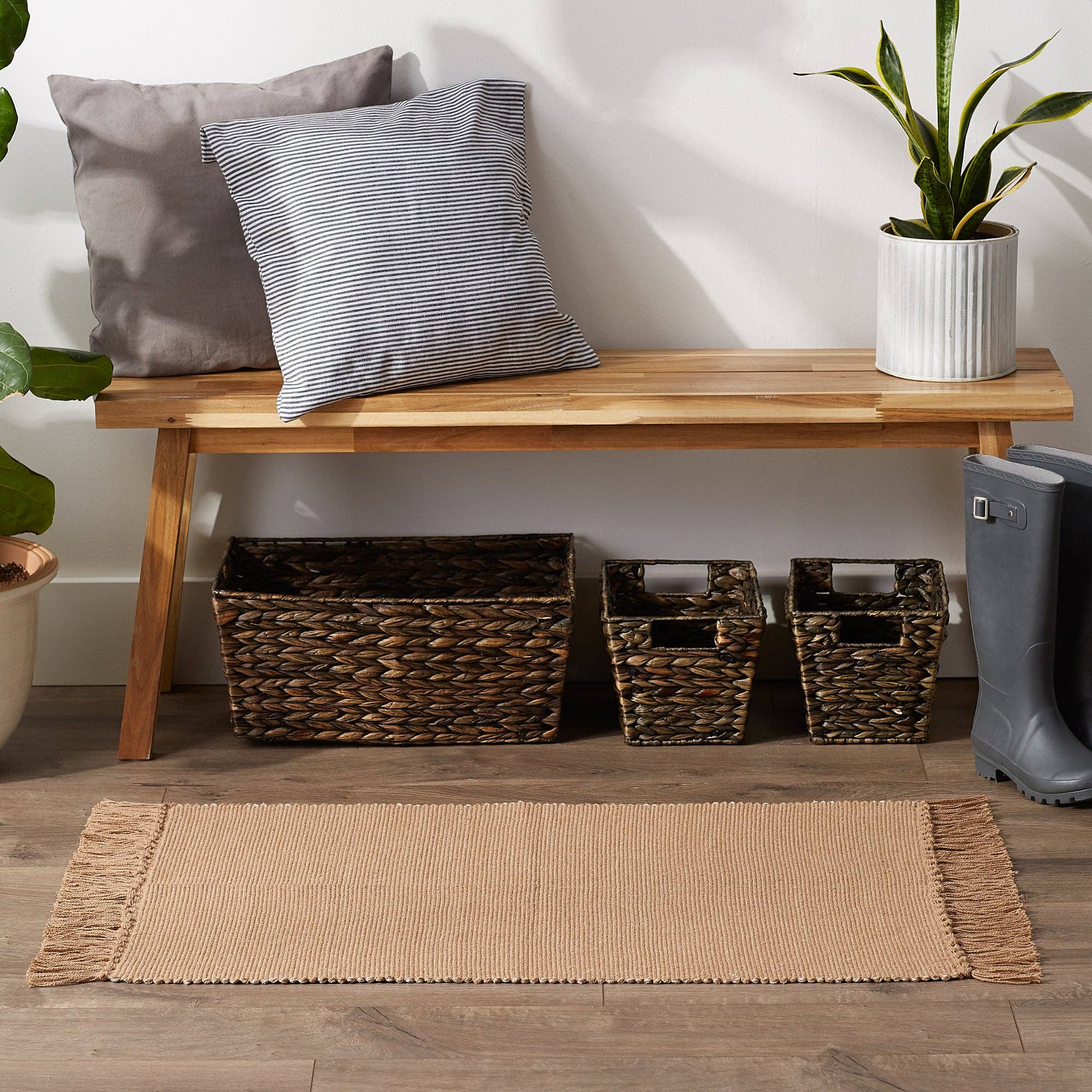 Wooden bench with cushions, baskets, and a plant in a room setting.