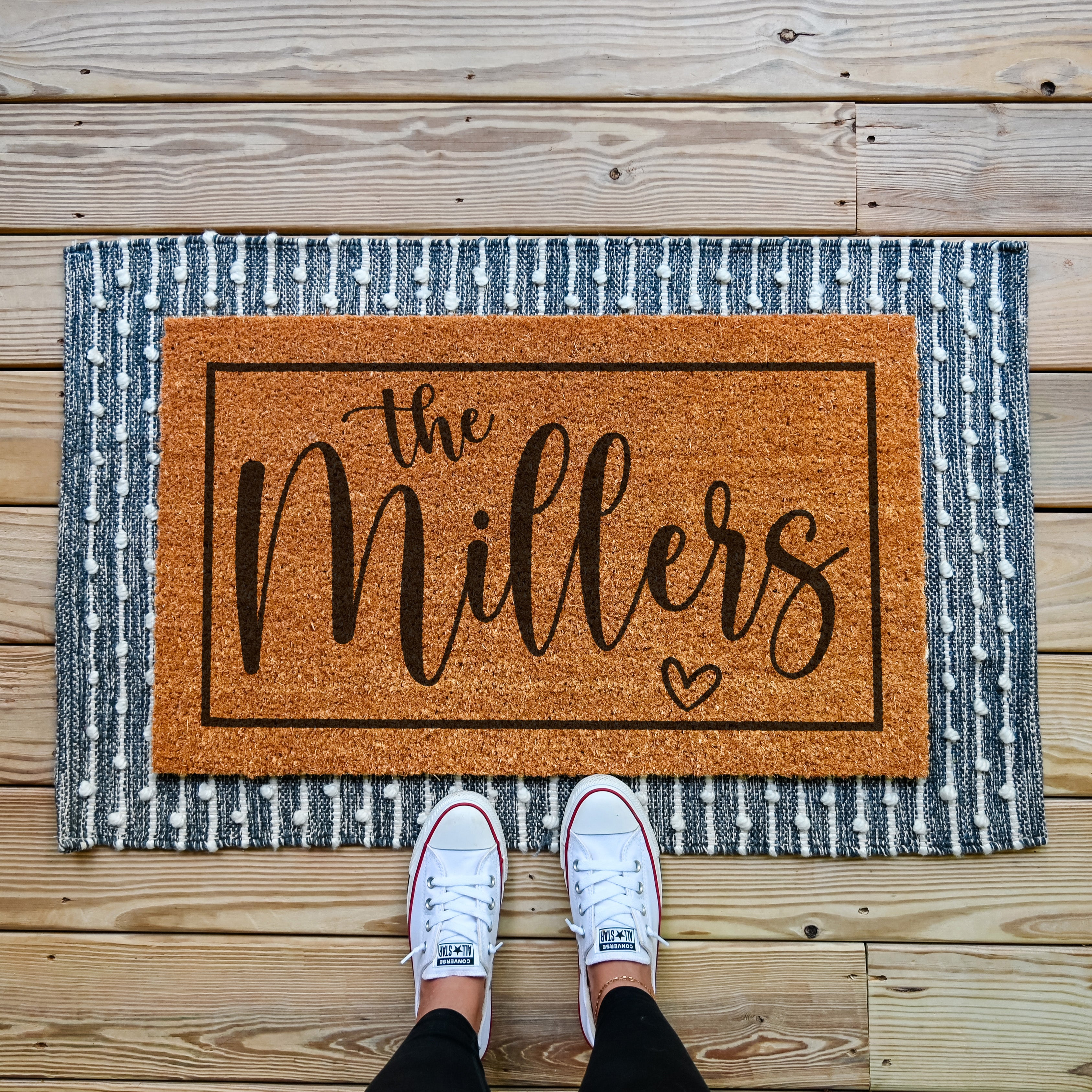 Personalized doormat that has a border around the edge. The sample reads The Millers and has a small heart outline under the name.