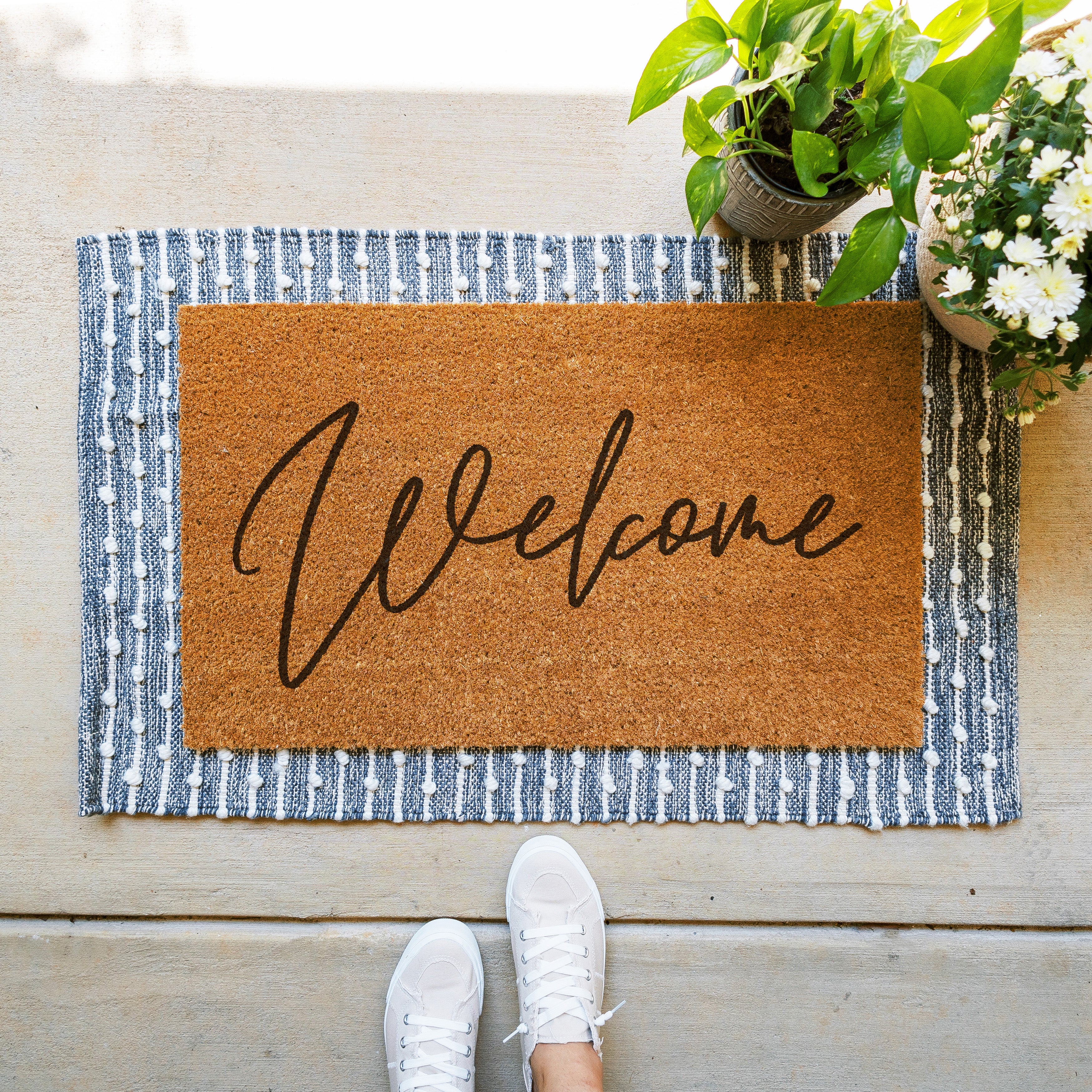 coir doormat that says welcome in a fun cursive font