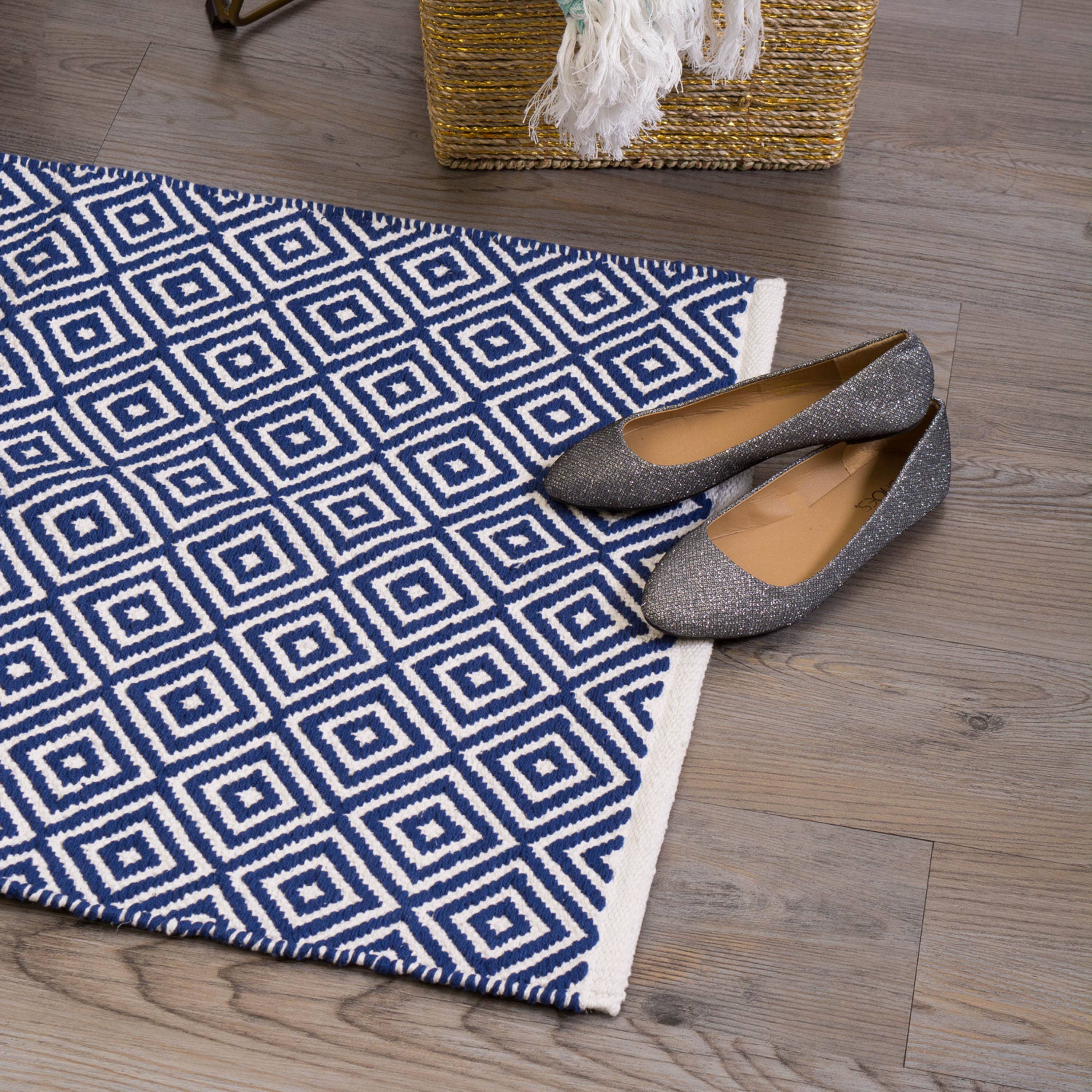 Blue and white geometric patterned rug with shoes on a wooden floor